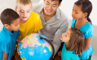 diverse kids looking at a globe with a teacher