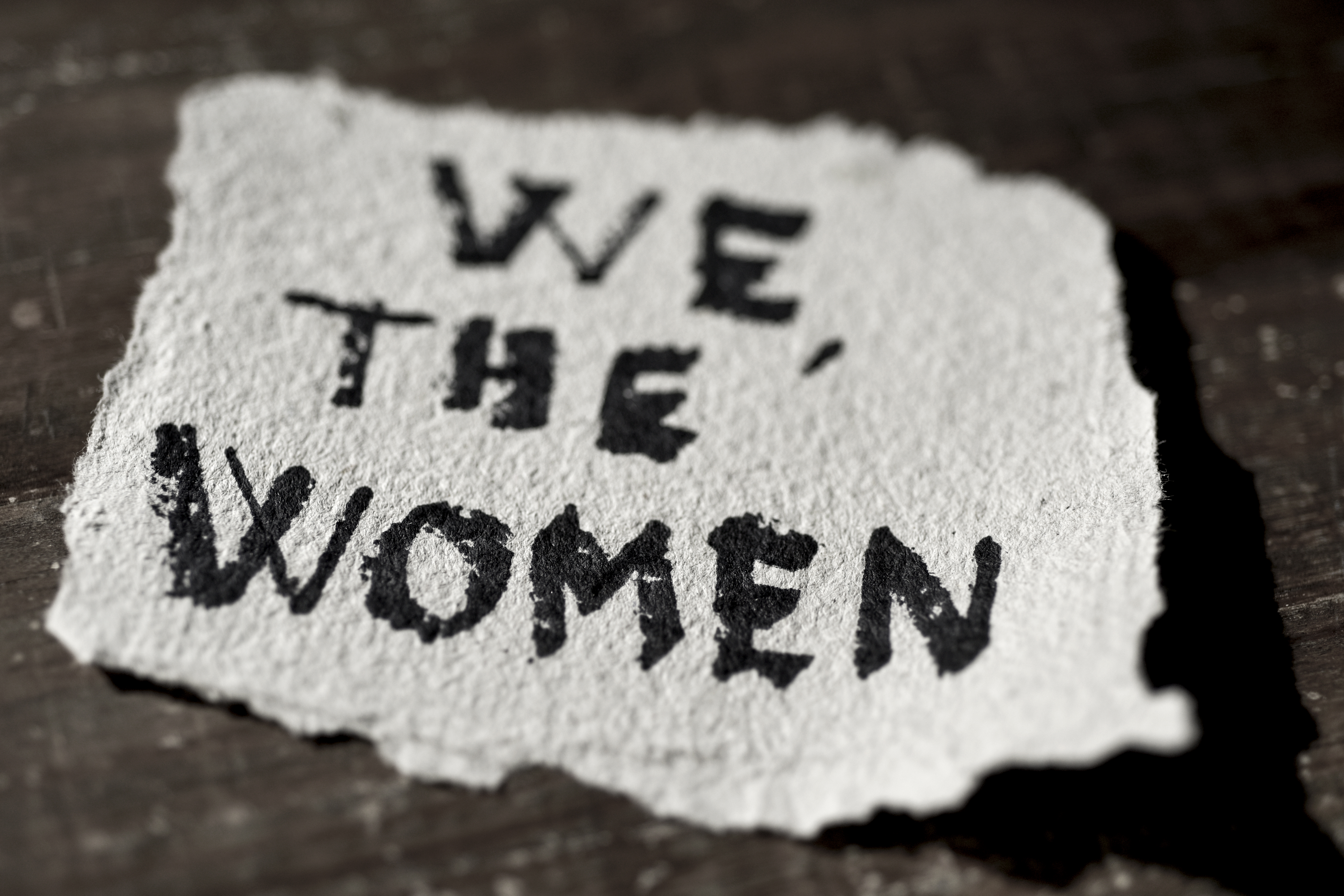 piece of paper with "We, the women" written in black ink.