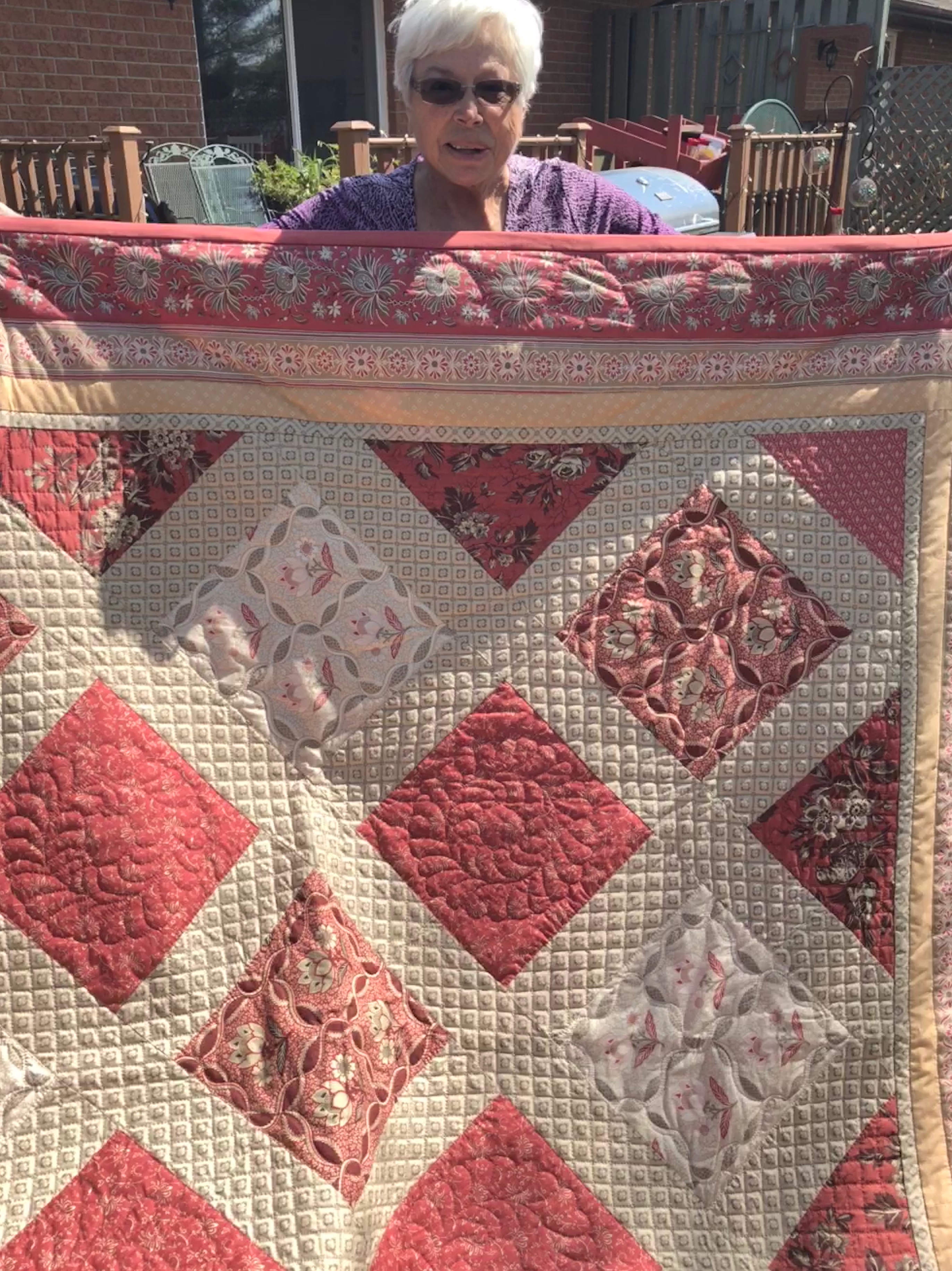 Geraldine holding a quilt that she made.