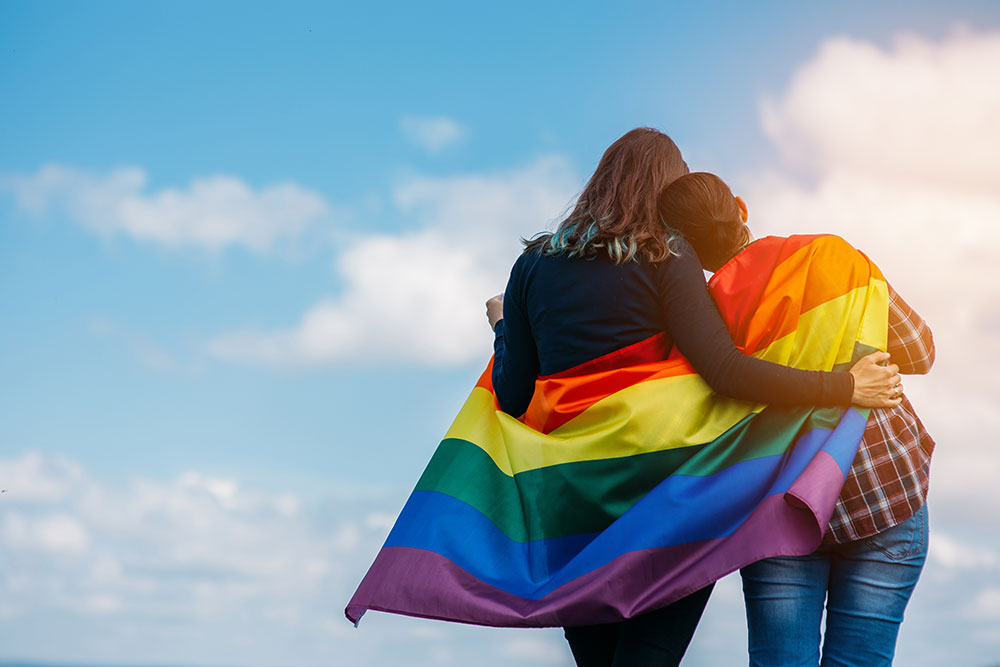  couple hugging outdoor with LGBT rainbow flag